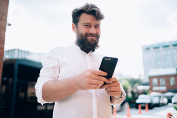 Obraz na płótnie Canvas Smiling adult man with smartphone in city