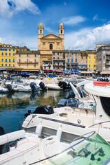 view on &eacute;glise Saint Jean-Baptiste in Bastia from the vieux port with some boats resting in the habour during summertime