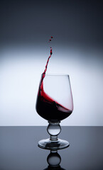 red wine splashing out of a glass. glass of red wine on black glass