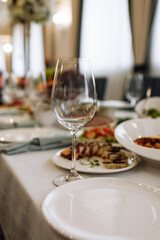 Empty glasses set in restaurant. wedding, decor, celebration, holiday concept - romantic table setting with white tablecloth, plates, crystal glasses