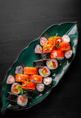 set of sushi roll with salmon, avocado, cream cheese, cucumber, rice, caviar, eel, tuna in plate on black background