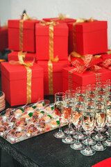 Red gift boxes wrapped in craft paper with golden ribbons and bows. set oh glasses of champagne