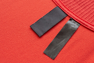 Blank black laundry care clothes label on red fabric texture background