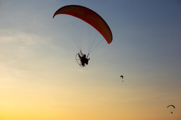 Paragliders flying with a paramotors during beautiful sunset