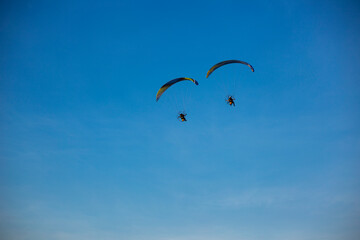 Two Paragliders flying with a paramotors during beautiful blue sky