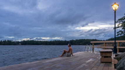 Finnish sauna. A man wrapped in a towel relaxing after swimming in cold water. Wooden bathhouse or...