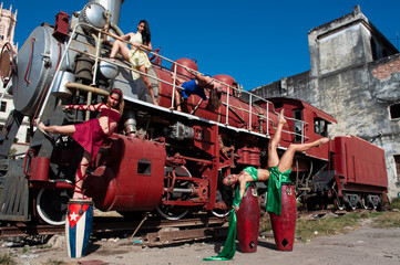Girls dressed in different colors posing on an old train with a drum in an ancient city