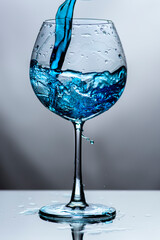 Blue water in translucent glass on white background.