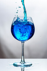 Blue water in translucent glass on white background.