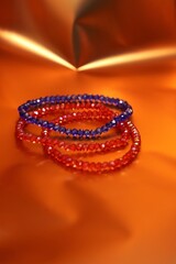 Three Blue and red color beaded crystal hand jewellery or bracelets isolated on beautiful orange or golden shiny background