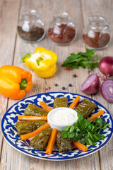 Fototapeta na wymiar plate with dolma and carrots slices with sour cream on wooden background, close vie