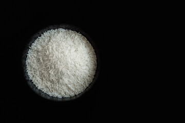 Rice in a bowl on black background top down view