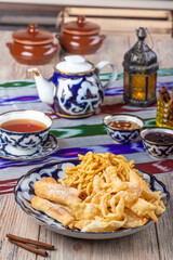 plate with crispy snacks with cup of tea on wooden background, close view, tea time concept 