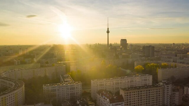 Scenic Hyper Lapse fast moving Time Lapse above Cityscape with Nature and Skyline, Berlin Germany TV Tower in golden hour sunset light, Aerial Establishing Shot