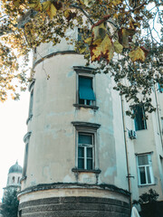 Fototapeta na wymiar old rounded building in the town with autumn leaves in the foreground