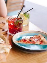 Italian cuisine pizza with ham and tomato paste along with pizza with pear and parmesan. On light wood cutting boards. Natural food. Italian restaurant. Natural lemonades with ice. City lifestyle