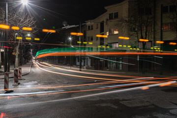 Fototapeta na wymiar Long exposure of trolleys in a street, creating green, red and orange lines of light