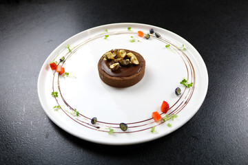 Chocolate dessert on a white plate. Decorated with berries and nuts.