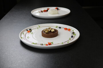Chocolate dessert on a white plate. Decorated with berries and nuts.