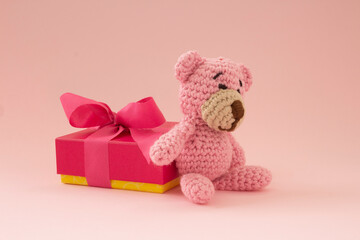 small crochet bear in pink with a gift box on the back. Pink color. Love concept.