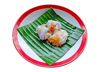 Multi color of Thai steamed rice dumplings dessert on green square banana leaf and red border round plate. Thai dessert isolated on white background.