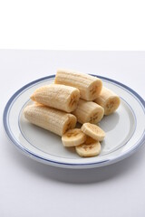 Superfood, vegan ingredients photographed on a high-key background, include bananas, blueberries, kale, soy milk, flaxseed milk, peanut butter, pumpkin seeds and salt.