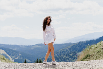 Tourism lifestyle of attractive girl. Young woman is walking is hiking in the mountains and smiling