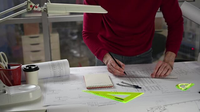 architect makes corrections on drawing at table with pencil and ruler