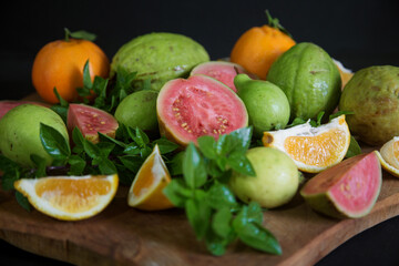sliced and whole guava and tangerine fruits with Basil leaves