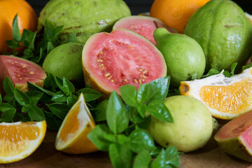 sliced and whole guava and tangerine fruits with Basil leaves