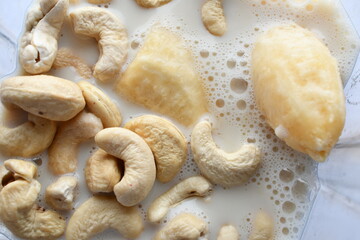 Superfood, vegan ingredients photographed on a high-key background, include bananas, blueberries, kale, soy milk, flaxseed milk, peanut butter, pumpkin seeds and salt.