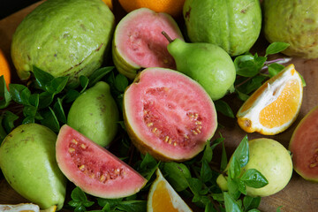 sliced and whole guava and tangerine fruits with Basil leaves