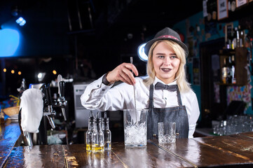 Girl barman creates a cocktail on the alehouse