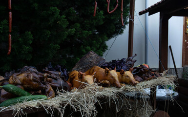 Whole grilled young pigs sit on a hay cart at a street food festival.