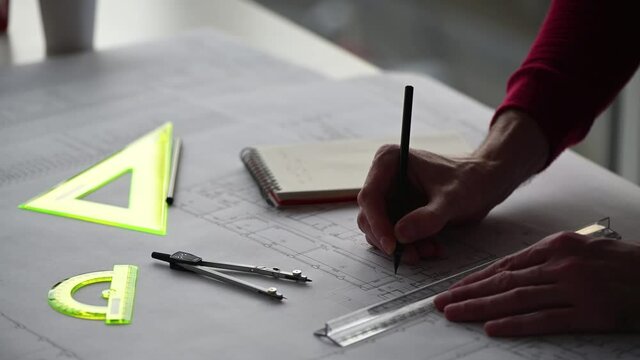 engineer makes edits to blueprint with a pencil