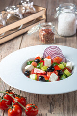 plate with Mediterranean Cucumber Salad on wooden background, close view 