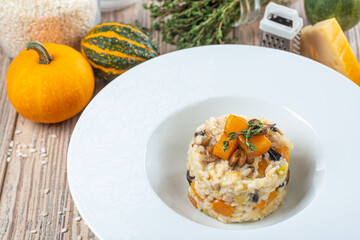 plate with creamy pumpkin rice on wooden background, close view, autumn and vegetarian concept 