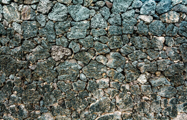 Wall of volcanic stones with grunge texture. Rock background lava abstract wallpaper.