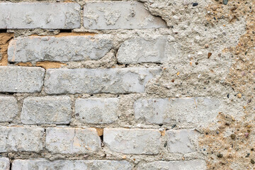Damaged plaster on a brick wall, white paint
