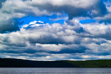 Clouds over the lake and forest in the background