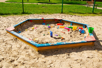 Piaskownica pełna foremek do piasku i zabawek na osiedlowym placu zabaw 