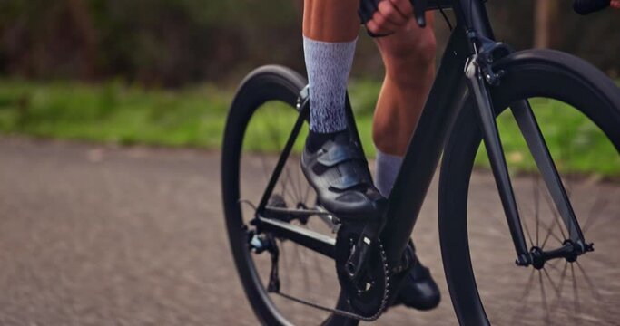 Wheels of black professional bicycle going uphill on asphalt road