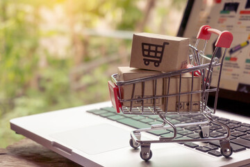 Shopping online concept - Parcel or Paper cartons with a shopping cart logo in a trolley on a laptop keyboard. Shopping service on The online web. offers home delivery..