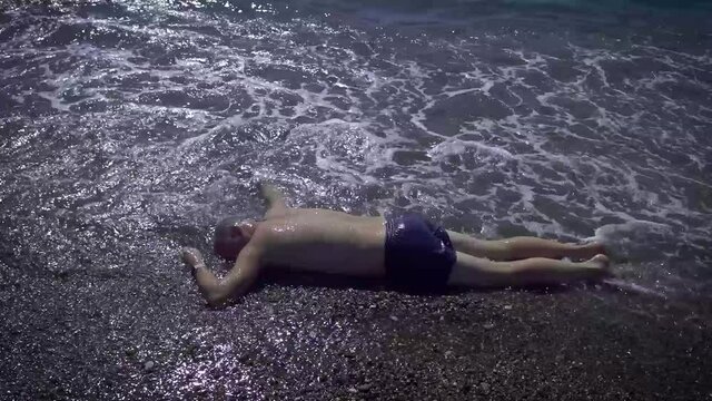 The body of a man washed up on the beach. A drowned man in swimming trunks who was neglected by safety rules on the water.