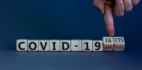Hand turns cubes and changes the expression 'covid-19 myths' to 'covid-19 facts'. Beautiful grey...