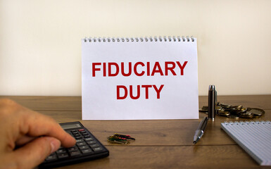 White note with inscription 'fiduciary duty' on beautiful wooden table, male hand on calculator, pen, paper clips, coins. Business concept. White background.