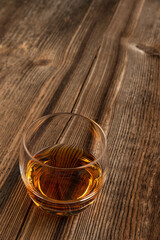 Szklanka z napojem na tle ciemnych, starych desek. Kamienne kostki ułożone w pobliżu szklanki. © Mikołaj Rychter