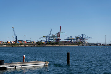 Port of Valencia view with shipping container terminal and cranes.Important harbour in Mediterranean Sea .Industry , transport and business concept background.