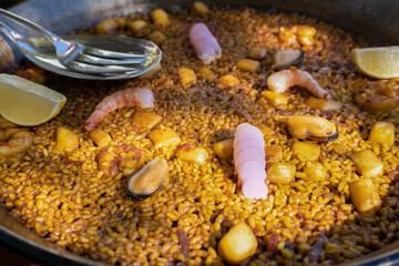 Paella traditional seafood spanish served in pan.Close up view of the famous dish with delicious ingredients prawns , squid,mussels ,clams , vegetables and rice.