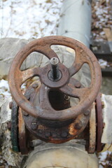 Old damaged and rusty iron oil pipe valve wheel. Metal, pipeline and mechanic concept. An old iron valve on a gas pipe. A valve to cover the pipe with a round handle